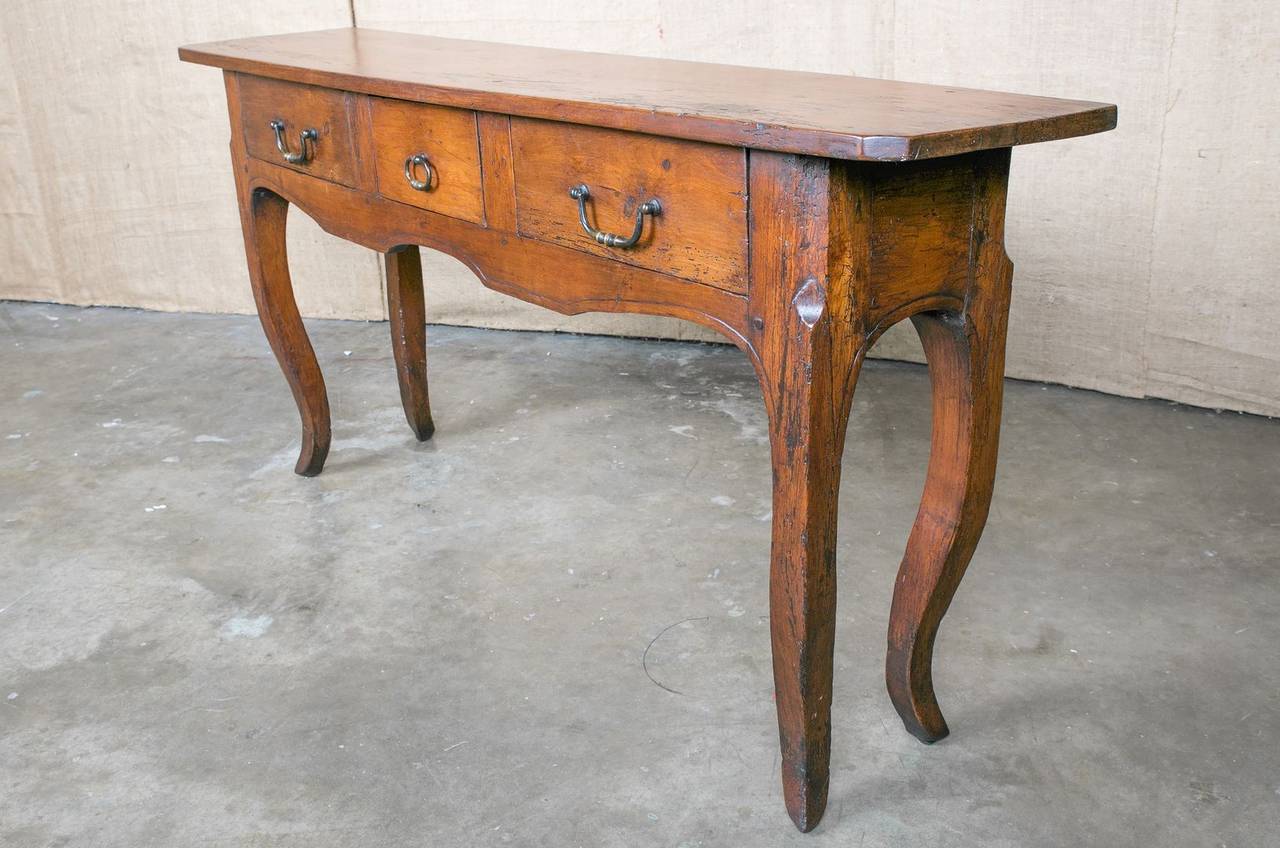 Lovely Country French sofa table/console converted from an antique farm table.  Cherry wood. The carved apron houses three drawers with original bronze pulls. Resting on cabriole legs ending in pied de biche (hoof feet).