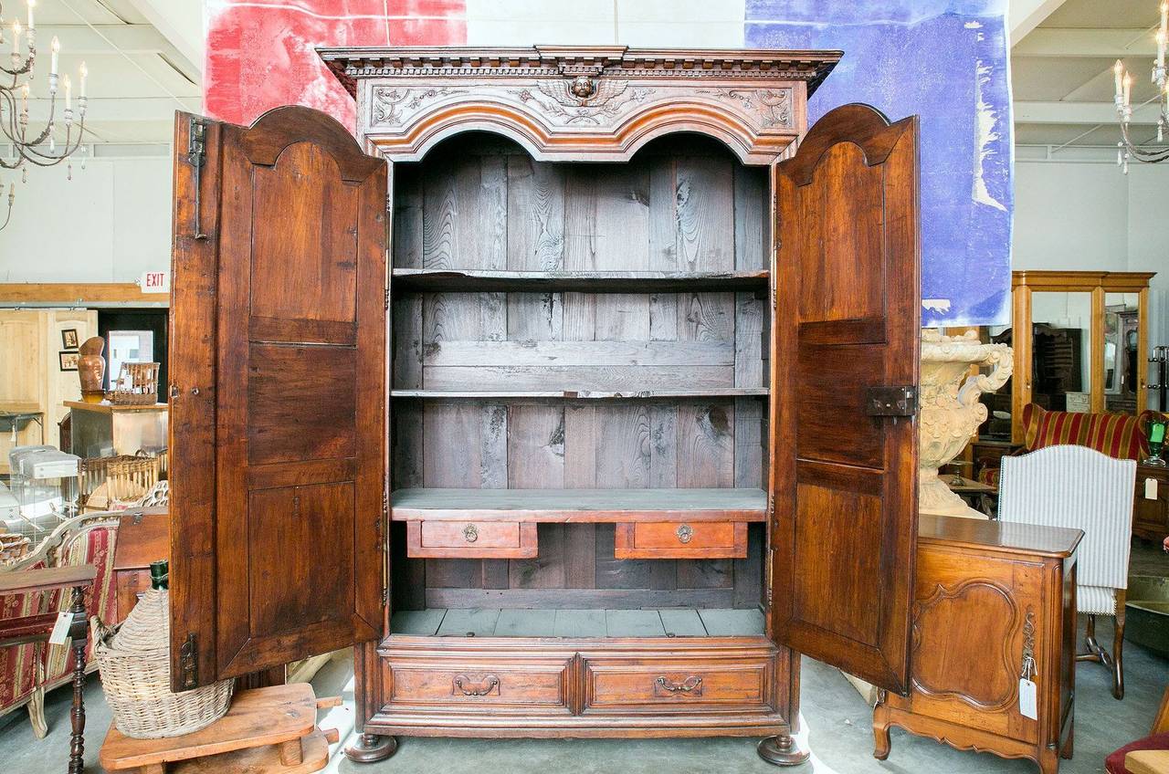 Exceptional 17th century transitional armoire handcrafted by talented artisans from Rennes during the early years of the reign of Louis XIV. The crown, with rows of dentil moulding, sits above a beautifully carved frieze with a central putti. Double