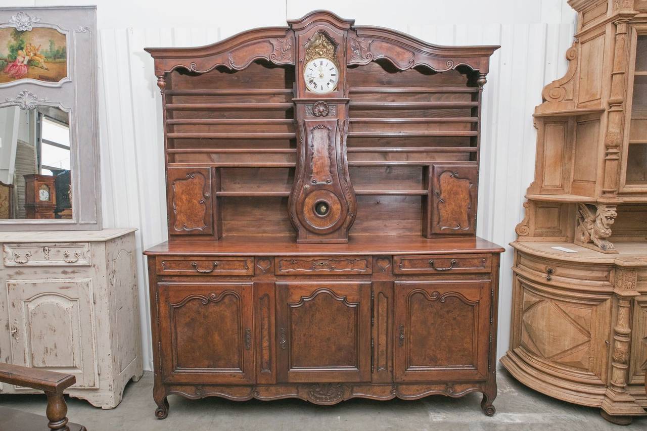Beautiful Country French vaisselier handcrafted of walnut and burled walnut in the typical technique mastered by the artisans of Bresse, circa 1850s. Upper section with open plate racks and two cabinets with a lovely longcase clock in the center,