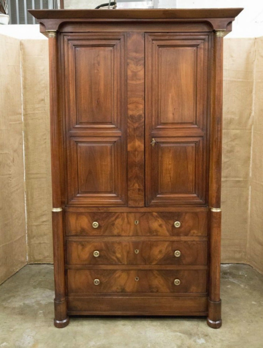 Fine French Empire period linen press of monumental size, handcrafted of walnut with a bookmatched front by master artisans from the Lyon region of France during the First Empire of Napoleon. Two upper cabinet doors flanked by columns fitted with