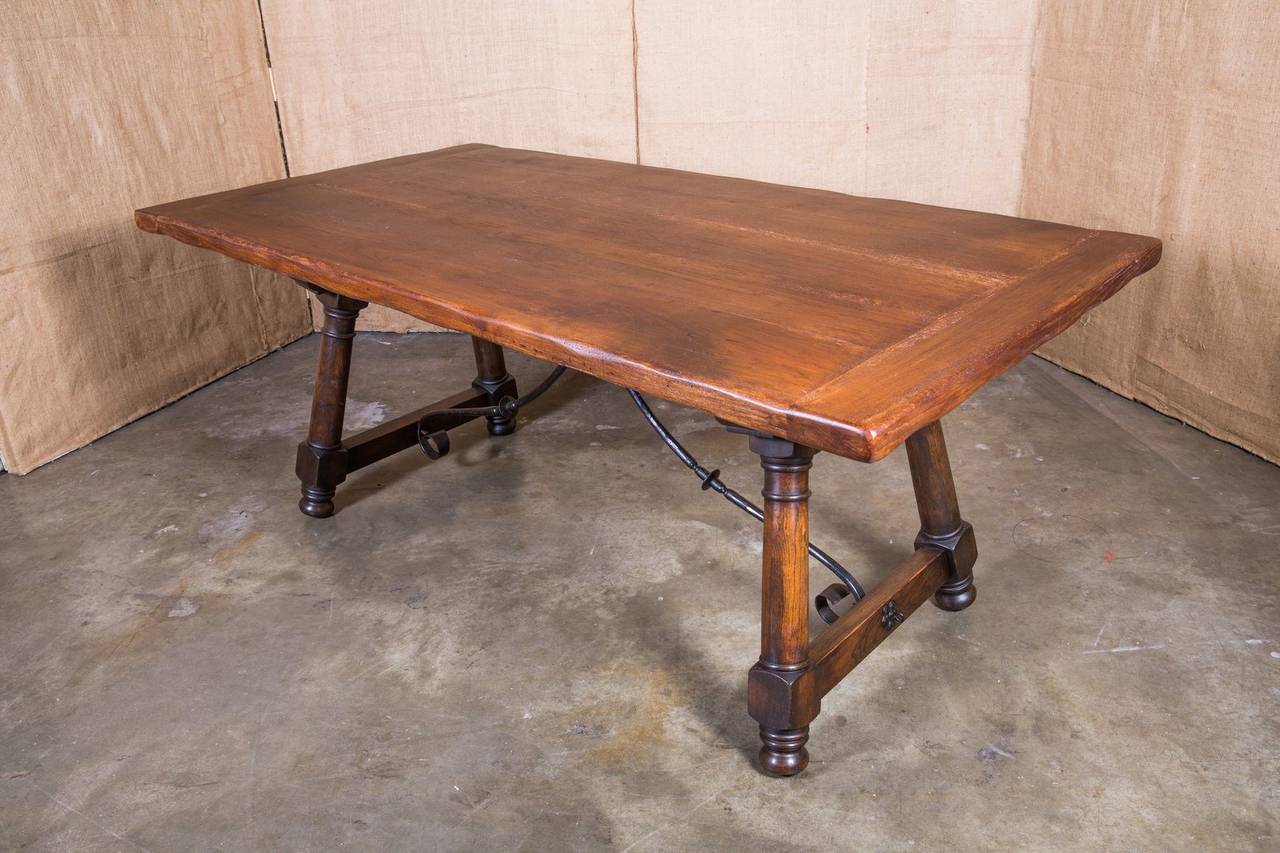 Handsome early 20th century Spanish trestle table with iron stretcher and rich patina. Solid oak plank top rests on a chestnut base with turned legs.