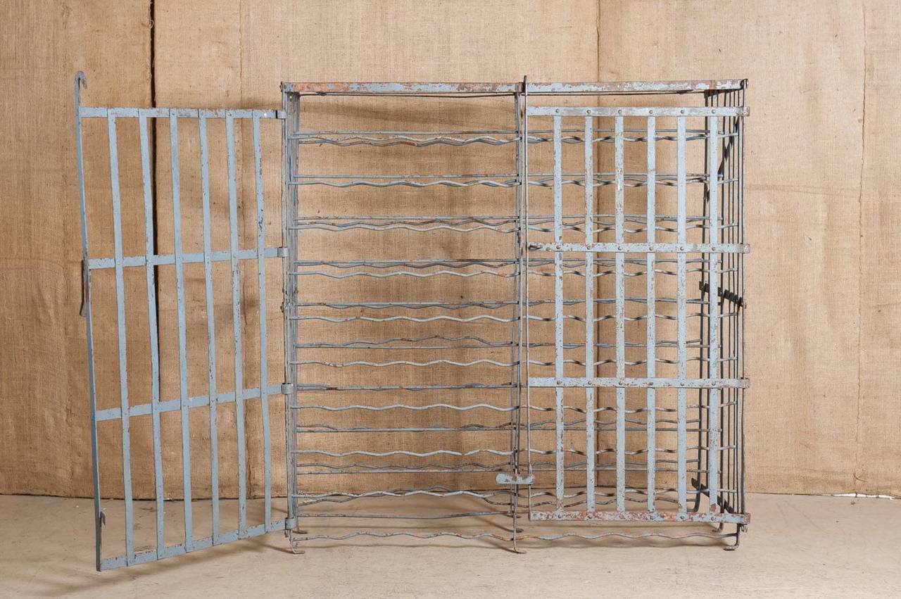 Early 20th century French wine cage. Hand forged of solid iron. Can be used mounted to the wall or as a free standing unit. Double banked with 200 fitted slots for wine bottle storage. Pair of hinged doors with locking clasp to secure priceless