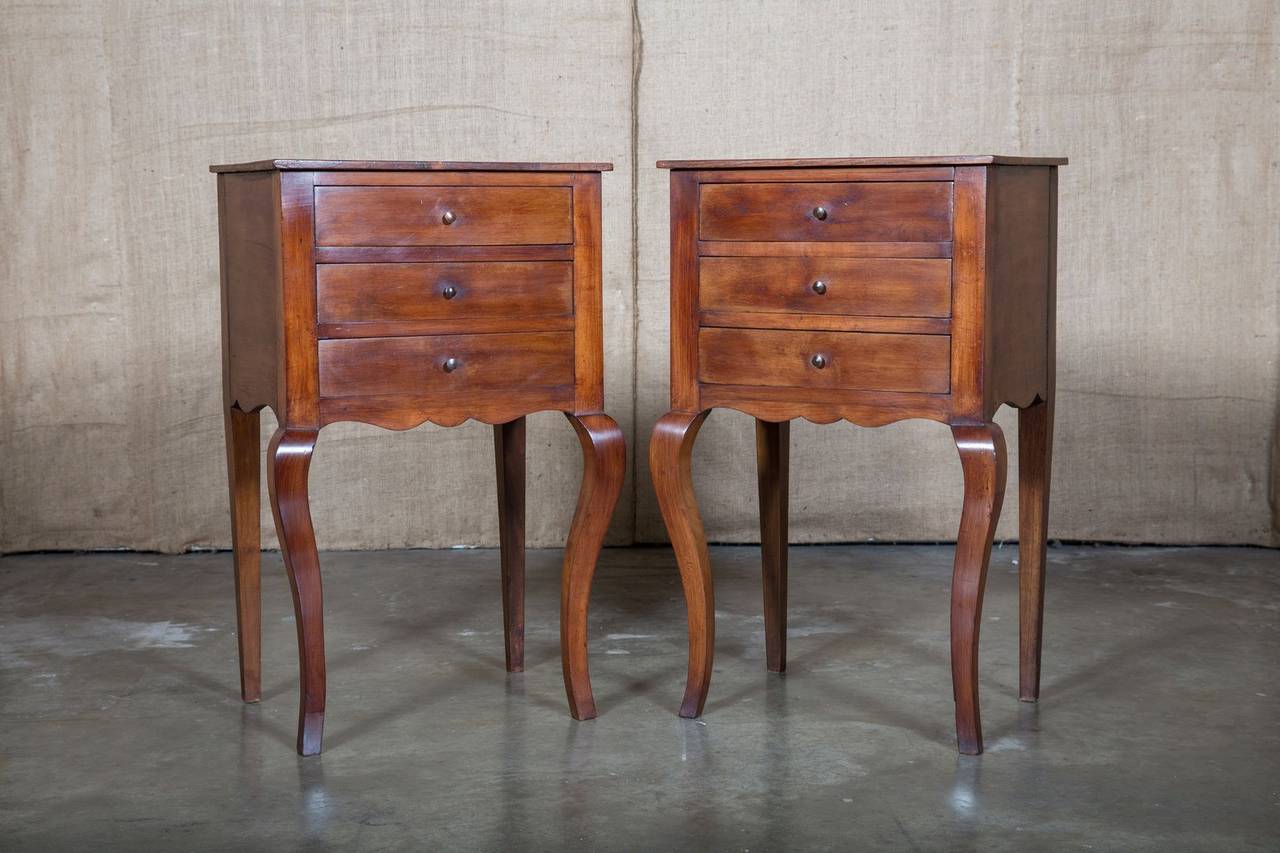 Charming pair of late 19th century cherrywood French Provincial chevets with classic Louis XV style. Three drawers above a scalloped apron, raised on graceful cabriole legs. Perfect as side tables or nightstands.