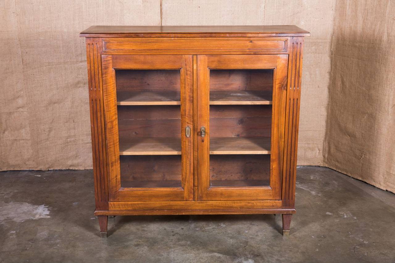 French Directoire style vitrine or bookcase with glass front doors and two adjustable interior shelves. Designed to showcase prized possessions or special collections, this solid walnut vitrine or bookcase from Lyon, is typical of the Directoire