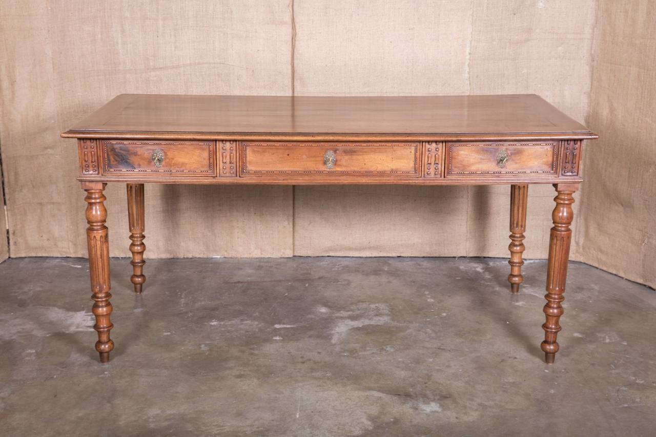 Handsome Louis XVI style bureau plat (writing table) from the Lyon region of France. Handcrafted of solid walnut, this desk has a wonderful aged patina. Three large and deep front drawers with beading, each having its own lock and key. Three faux