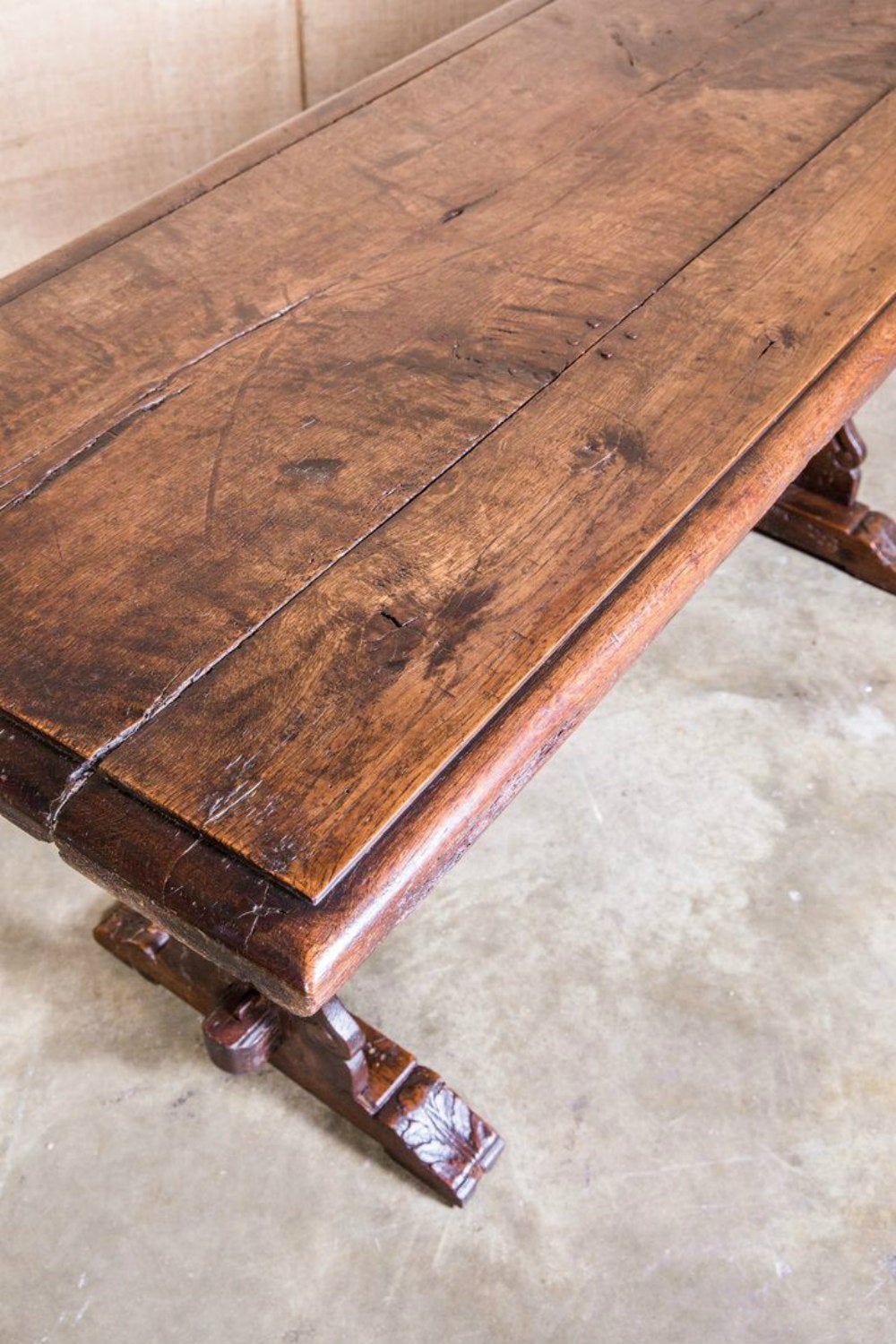 Charming 18th century country French trestle base console or center table. Handcrafted of solid walnut with a beveled plank top raised by carved shaped supports with motifs typical of artisans from the Auvergne region. Joined by a straight stretcher