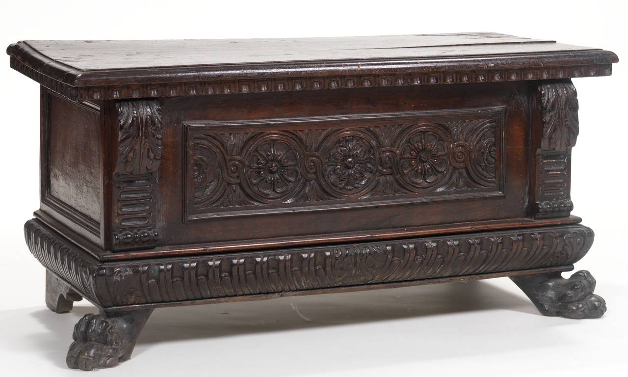 The rectangular hinged top carved with dentil molding over a floral medallion carved frieze centered by scroll supports, the scroll carved frieze raised on carved paw feet.