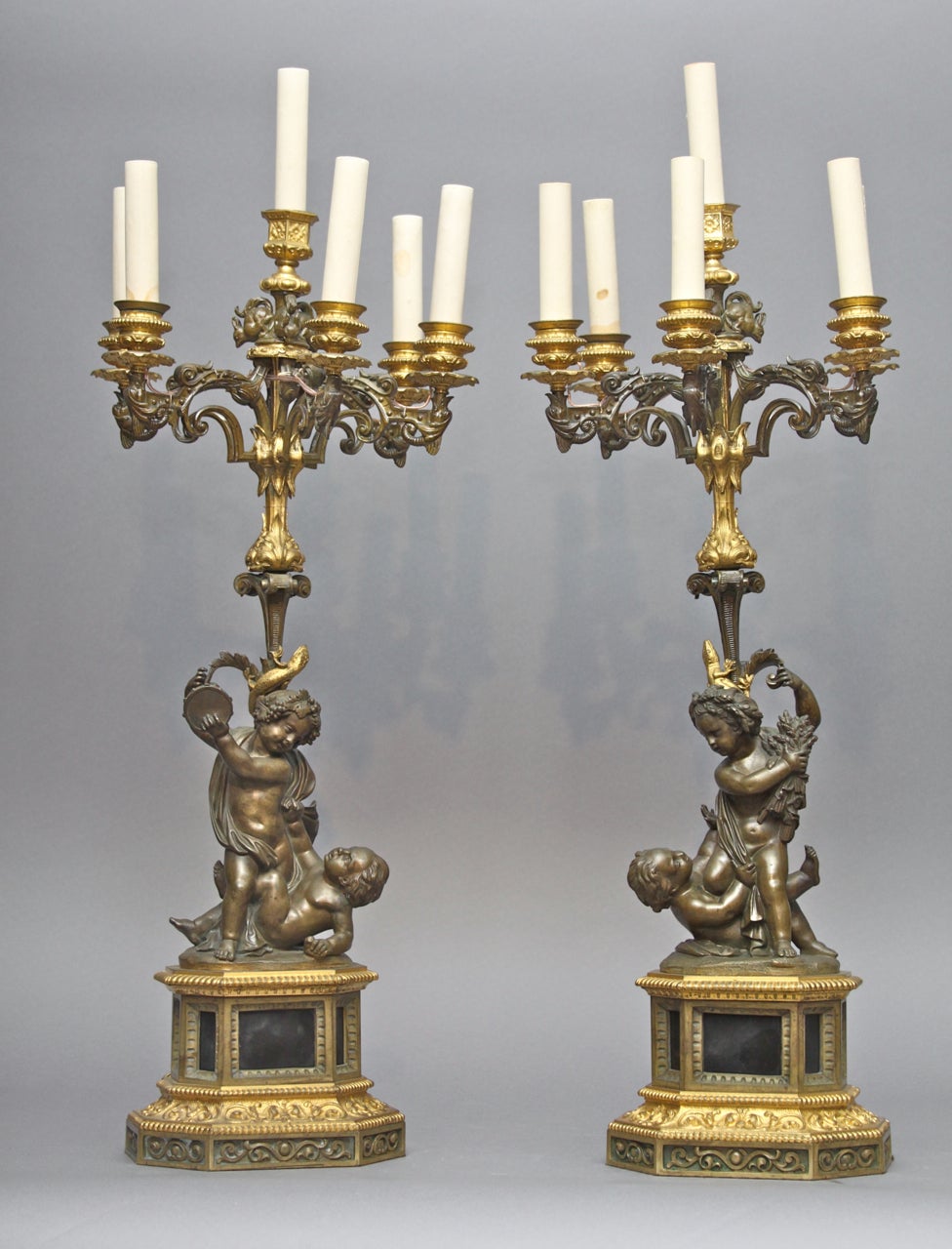 Each with a pair of putti wrestling, the standard cast with lizards, supporting six scrolled candle arms and one center candle surrounded by three squirrels, raised on hexagonal bases. Fitted for electricity.