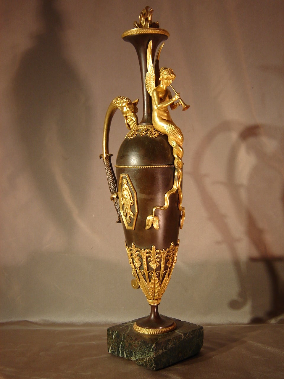 Exceptional ewer in chiseled and gilded bronze and patinated bronze from the early 19th Century, Empire period, attributed to Claude Galle (1759-1815).

Présence d'une sirène musicienne adossée au col de cette aiguière surmontée d'une flamme, anse