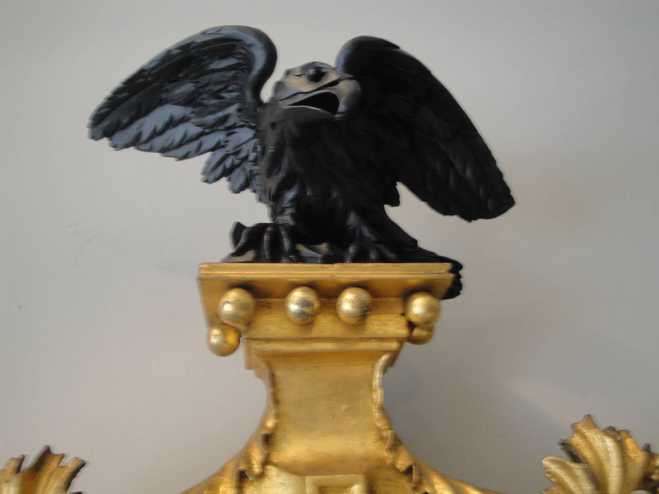 English Regency convex mirror, gilded and ebonized with eagle and acanthus leaves.