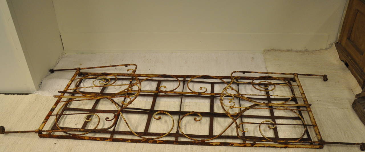A French hand forged iron bed with scrolling design and raised on castors .