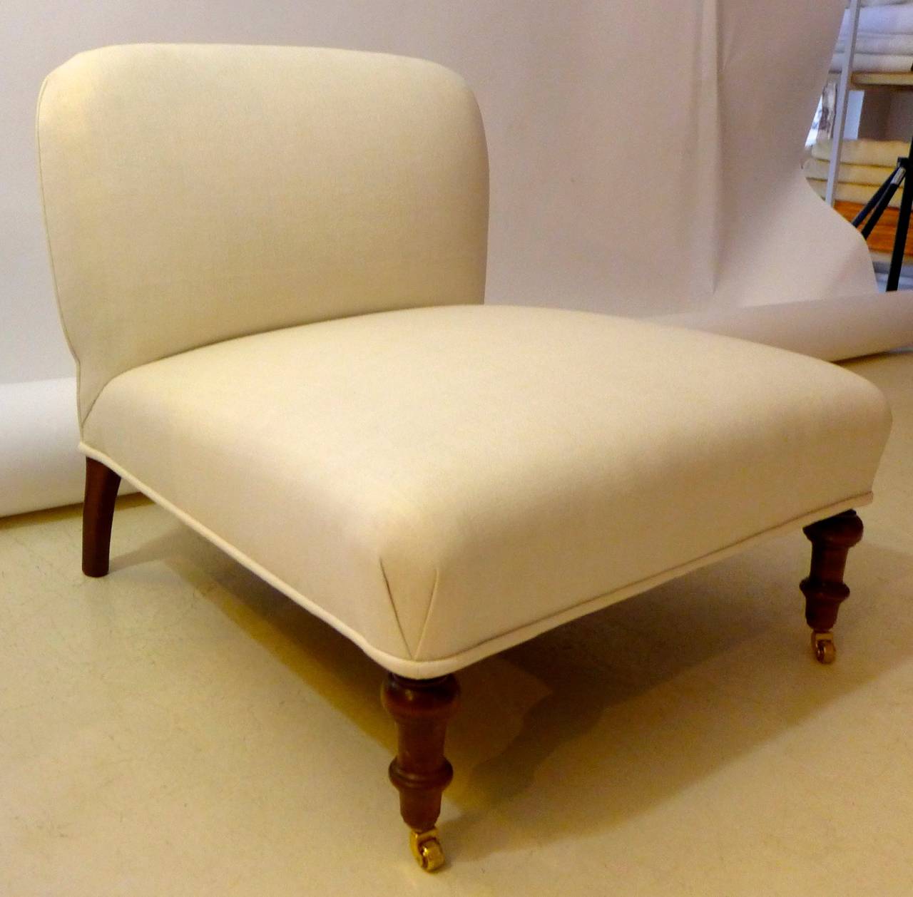 A French slipper chair in Napoleon III Style with turned wood legs on wheels in front. This chair is restored in the traditional way with copper springs and horsehair and upholstered with an off- white bleached hemp.