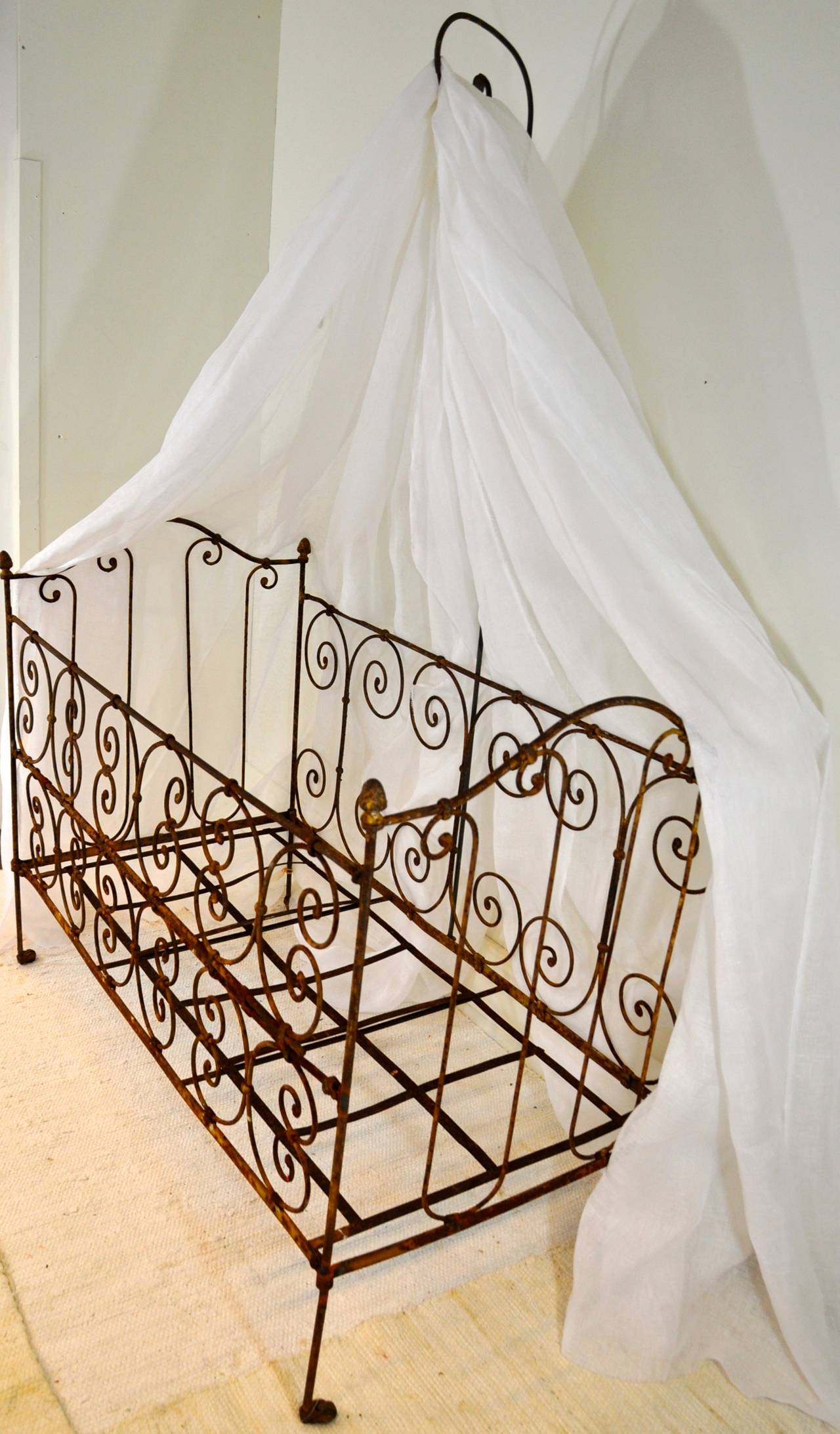 An 18th century French wrought iron folding baby bed with sky. This wrought iron bed is decorated with a scrolling design and raised on castors, while the approach of the bed is more comfortable because of the front that can be folded two times. The