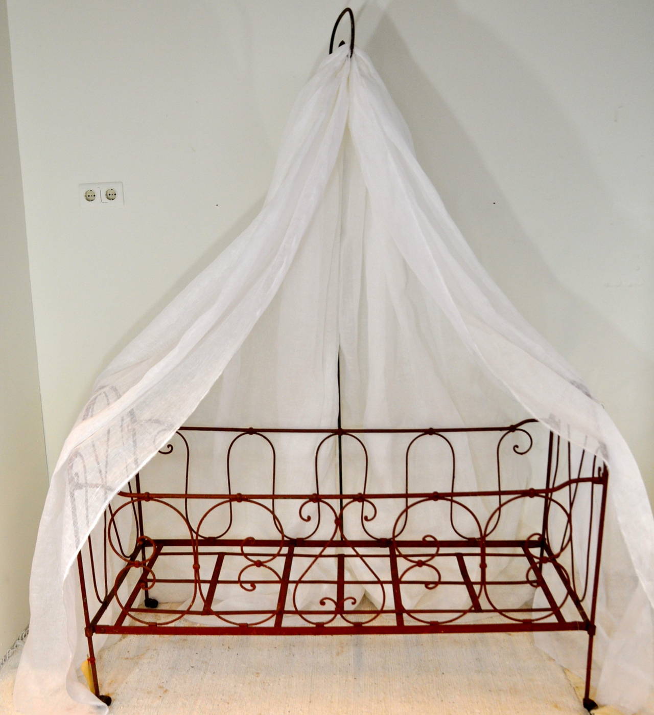 A 19th century French folding baby bed with sky. This baby bed is made in wrought iron with scrolling design and raised on castors. The sky is of a white linen voile and fixed on a beautiful curved Stand. The sky and the Stand are separate and very