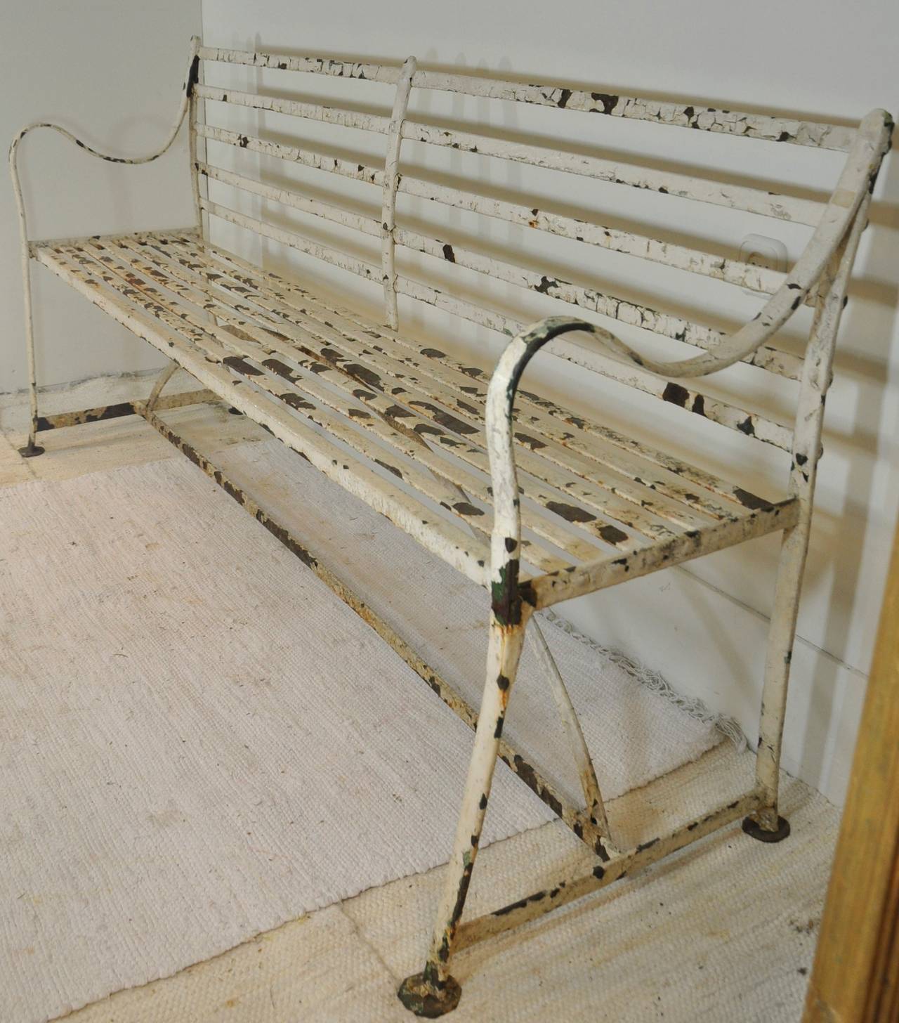 A charming 19th century wrought iron strap bench with a comfortable curved back. The structural condition is excellent. The paint is peeling showing some rust but can also be sandblasted, primed and painted.
