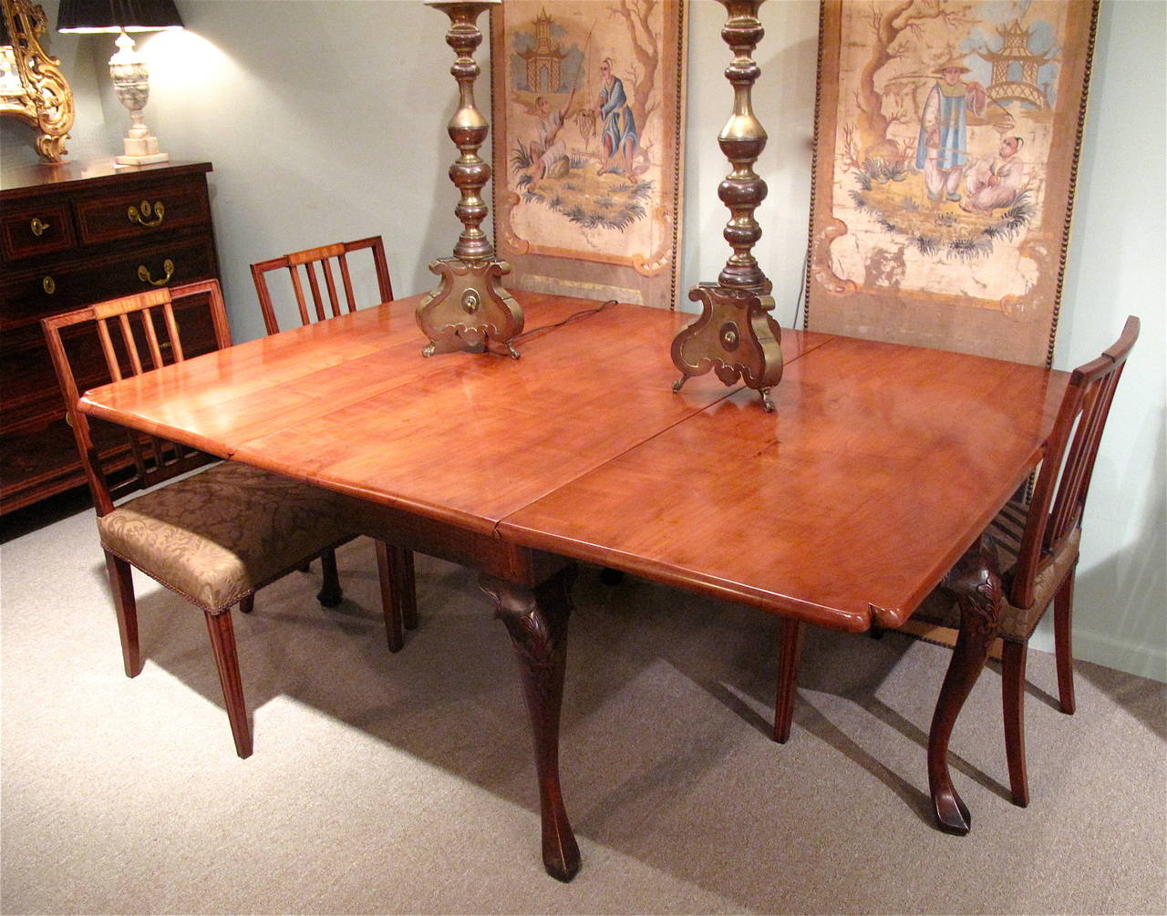 A rare English fruitwood dining table, ca. 1740, with a shaped top of light cherry, the legs of bold cabriole form, ending in squared and pointed pad feet. Each knee is handsomely carved with a symmetrical acanthus spray arranged like a fleur de