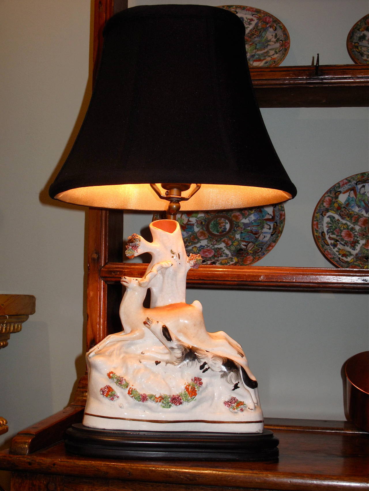 A late 19th century English Staffordshire figural group featuring an English setter chasing a stag, adapted into a lamp. Excellent condition with good detail including a delicate polychrome applied shredded clay garland.
