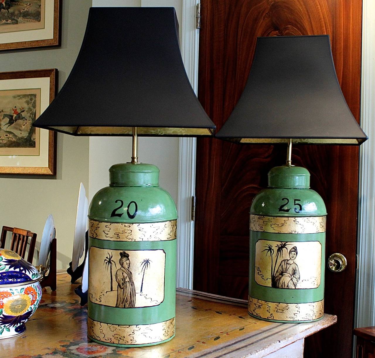 A pair of English tea cannisters adapted into lamps, redecorated with later painted and gilded chinoiserie decoration. Gold lined black “parchment” shades. 20th century.