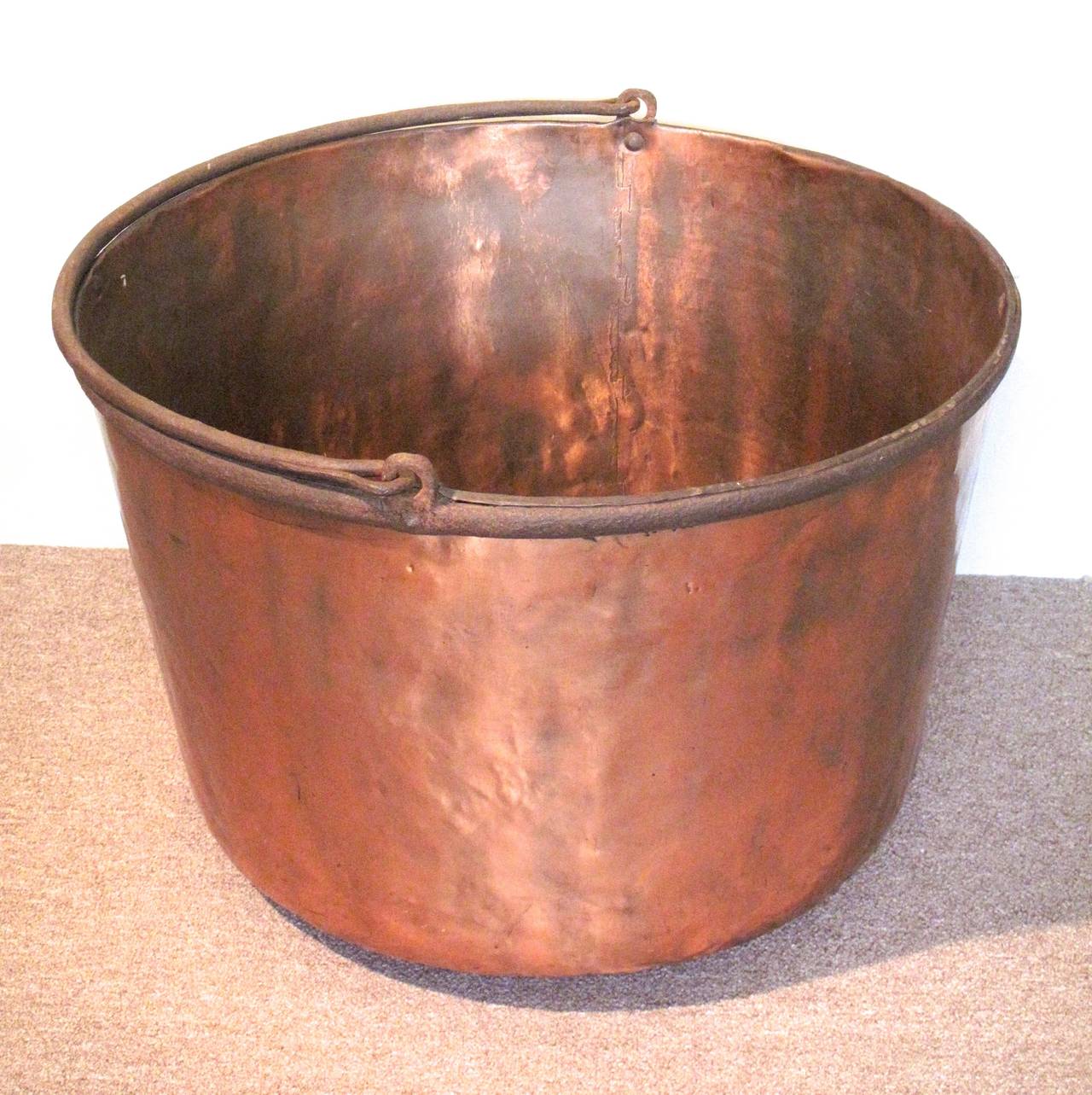 An exceptionally large and sturdy 19th century copper kettle with dovetailed construction and an iron rim and handle.