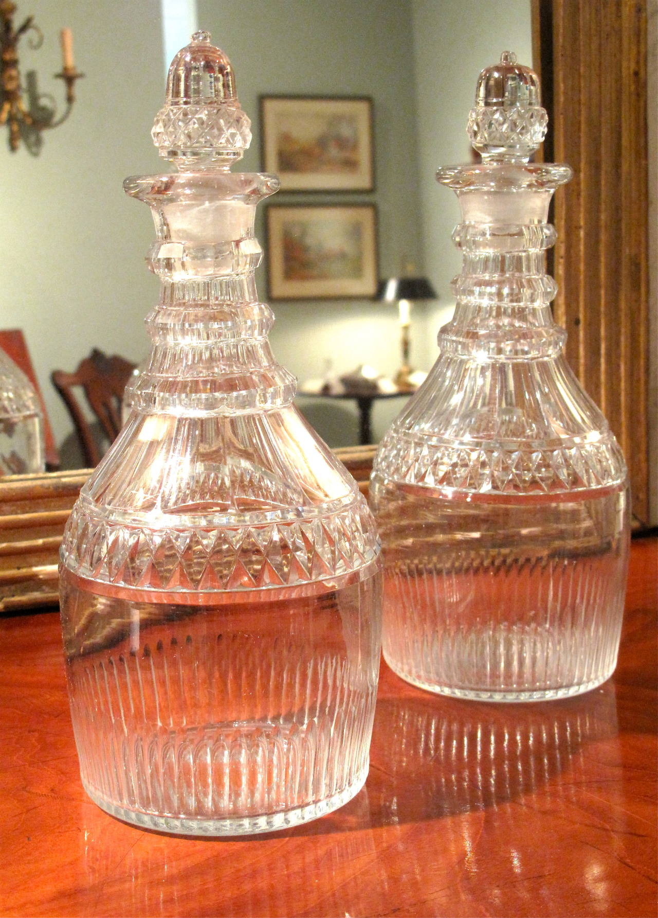 Blown then faceted and fluted, a fine pair of cut glass decanters, ca. 1800, with three ring necks and unusual acorn shaped stoppers.