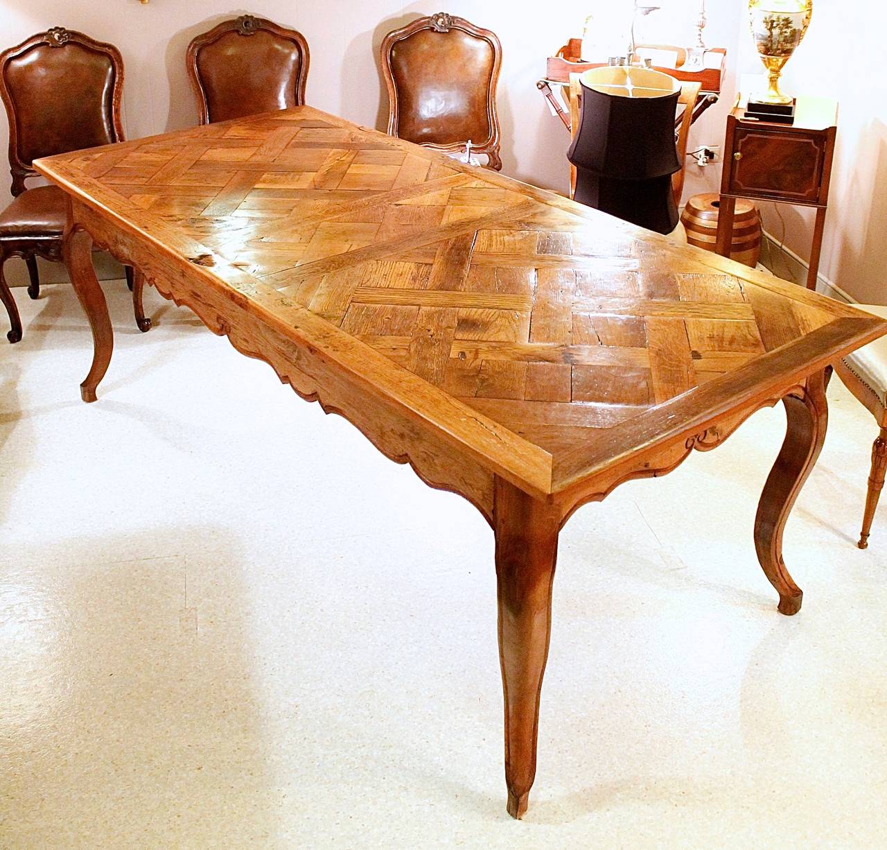 A provincial style French farm table composed of antique elements: the top being re-purposed parquet de Versailles flooring, fit to a table base with boldly out-swept cabriole legs supporting the frame with its attractively shaped rails. The table