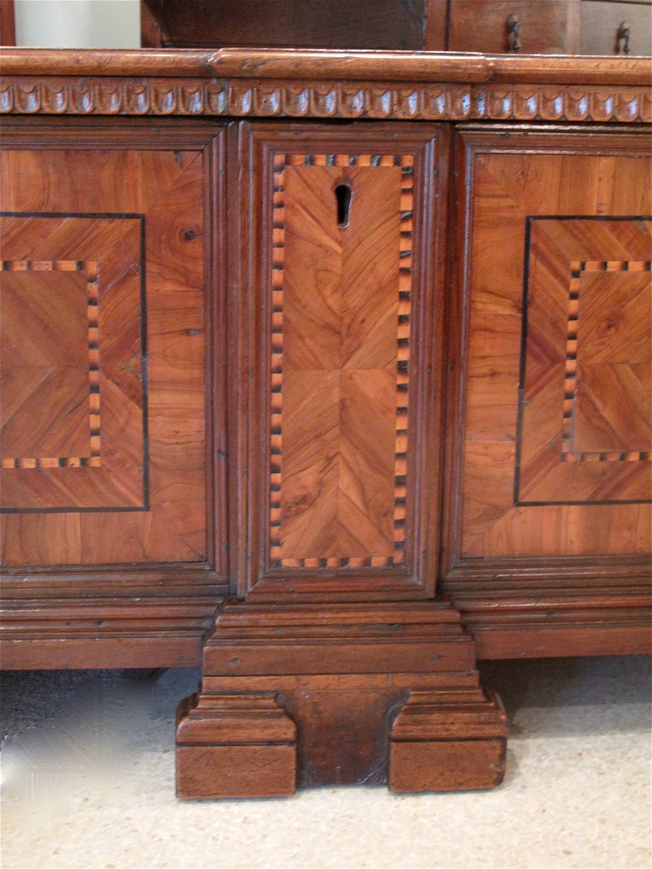 A dowry chest or cassone, from the second half of the 18th century, the front of somewhat architectural form, with a footed plinth and projecting “pilasters” separating the marquetry panels. Original strap hinges. Cassoni were given by the bride’s