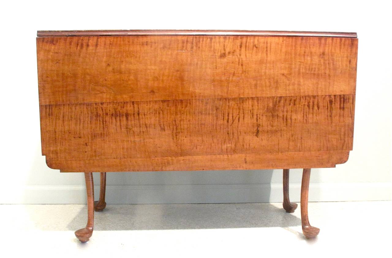 A Queen Anne rectangular drop leaf  table, ca. 1760, of wonderfully figured and patinated tiger maple. Finely tapered cabriole legs on pad feet support gracefully shaped table ends. Likely Connecticut or Massachusetts.