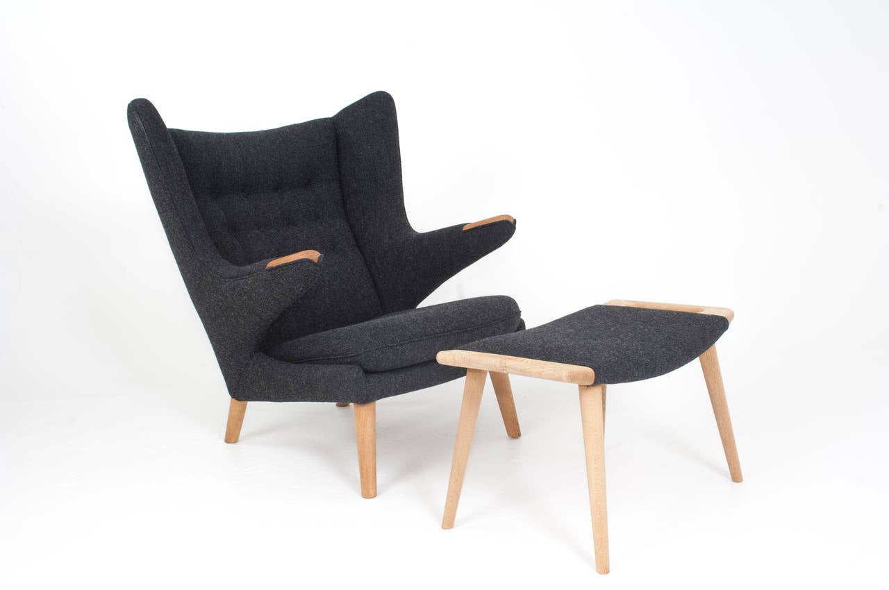 Hans J. Wegner papa bear chair and ottoman, model AP19 and AP29.

Teak nails, oak legs. (Ottoman in oak) new dark grey fabric upholstery, executed as original.

(Ottoman also available in teak).