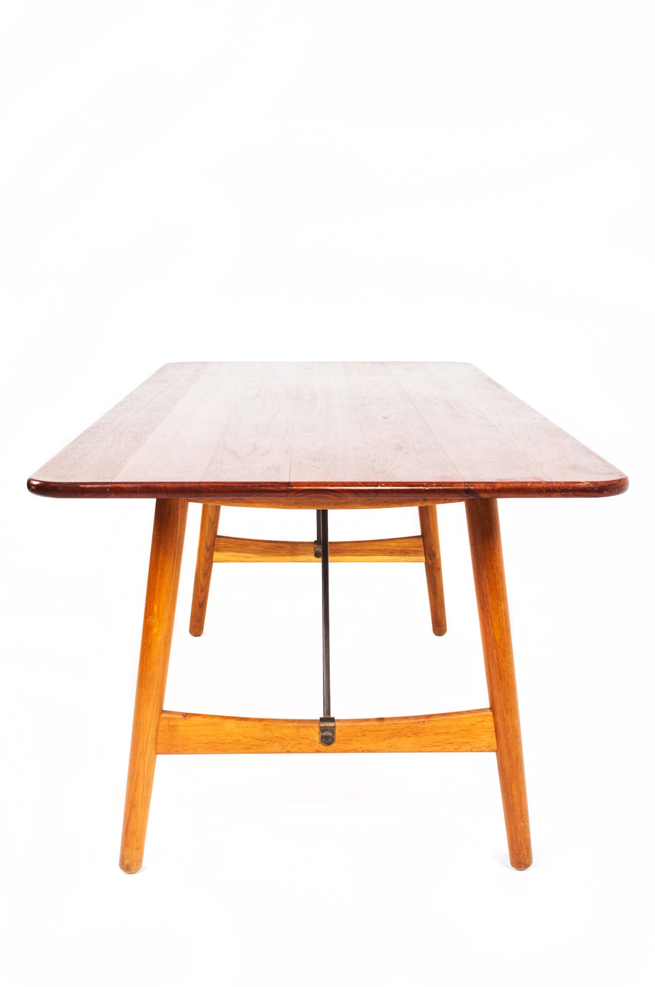 Børge Mogensen. Hunting table. 
Massive teak top with rounded corners. Solid oak base with brass bars.

Designed in 1950. 
Produced by Søborg Møbelfabrik

Measures: H 72, L 180, W 90 cm.