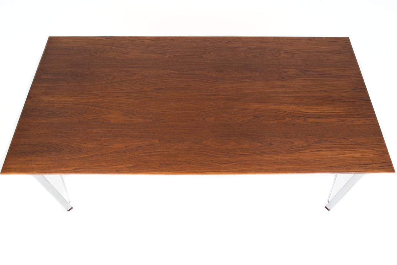 Arne Jacobsen teak table, model 3605, matte chromed steel legs and stretchers, rosewood leg caps.

Designed 1955.
Produced by Fritz Hansen.

Measures: H 70 cm, L 182 cm, W 90 cm.