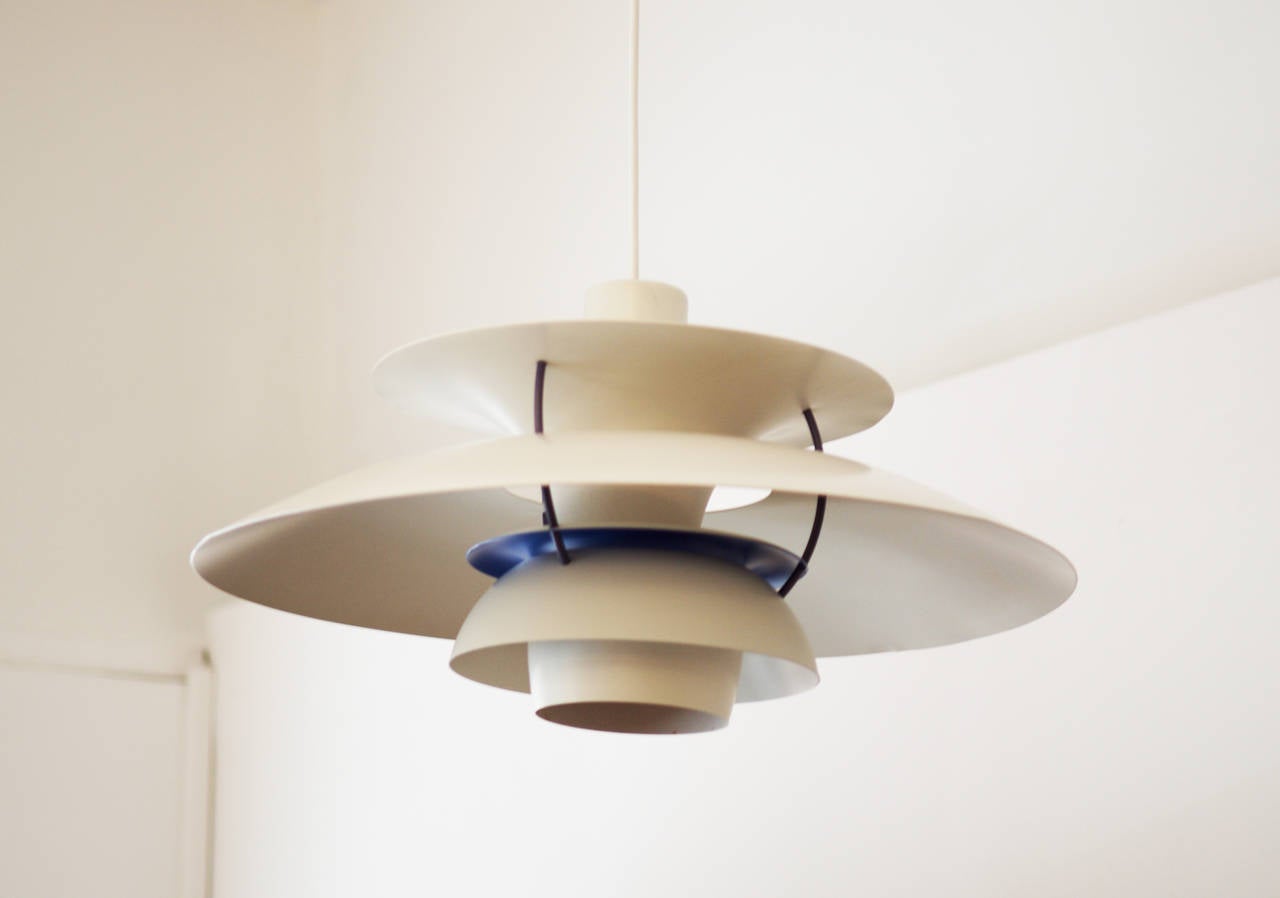 La lampe a été conçue par Louis Poulsen.
Conçues pour être suspendues au-dessus de la table, elles créent une lumière 100 % non éblouissante.
ces pendentifs ont des détails de bande violette sur le dessous et des bandes orange 
à l'étage