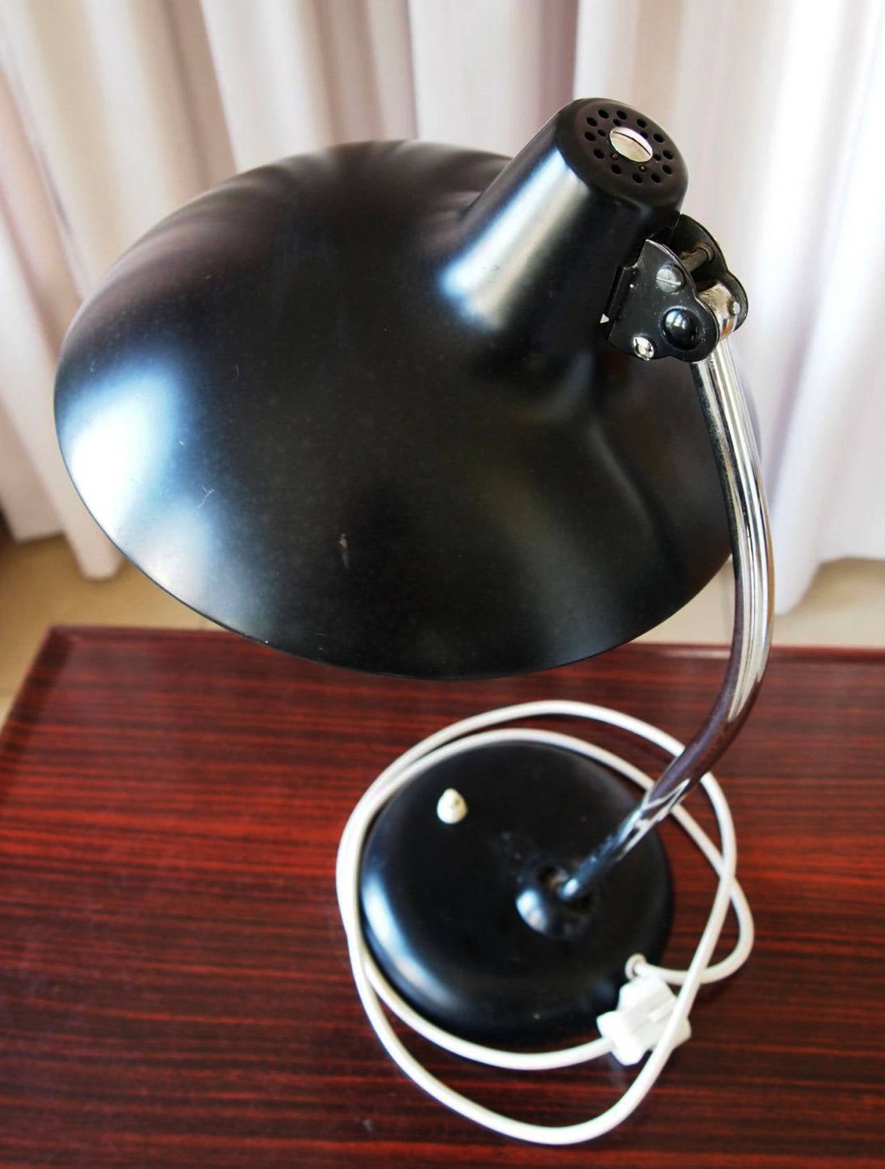 This 6786 model table lamp was designed between 1920-1940 by Christian Dell, and manufactured by Kaiser Idell in Germany and later by Fritz Hansen in Denmark. It features an adjustable black lacquered metal shade, with an adjustable chromed stem.