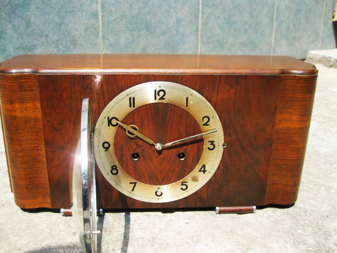 This antique HAU Hamburg Amerikanische Uhrenfabrik Art deco mantel clock was designed between the 1920s and 1940s.
It is made from softwood and covered with nut veneer. This item remains in a fair vintage condition and is in perfect working order.