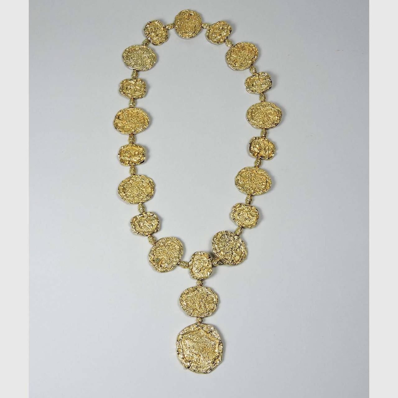 Cartier Gilt Silver Vermeil Necklace-Belt, circa 1970; 
marked Cartier, Sterling; Comprised of 19 silver gilt textured links with a 4” pendant drop 
Length: 29.5”

Note: A popular fashion accessory of the 1970’s, Jackie O’ was known to have