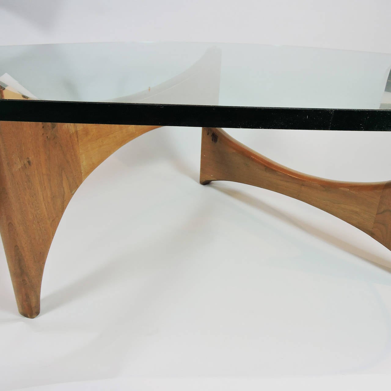 Mid-Century Modern glass and wood coffee table, manner of Isamu Noguchi. The adjustable curved wood base supporting a free-form glass top. 
Dimensions: 15 1/2 x 44 x 33 inches.