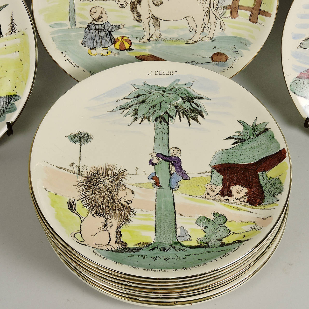 Early 20th century set of 12 comedic polychrome ceramic lunch plates by French designer and cartoonist, Benjamin Rabier (1864-1939), manufactured by Sarreguemmes, Paris. It is rare to find a complete set in good condition in color. 
Diameter: 7 3/4