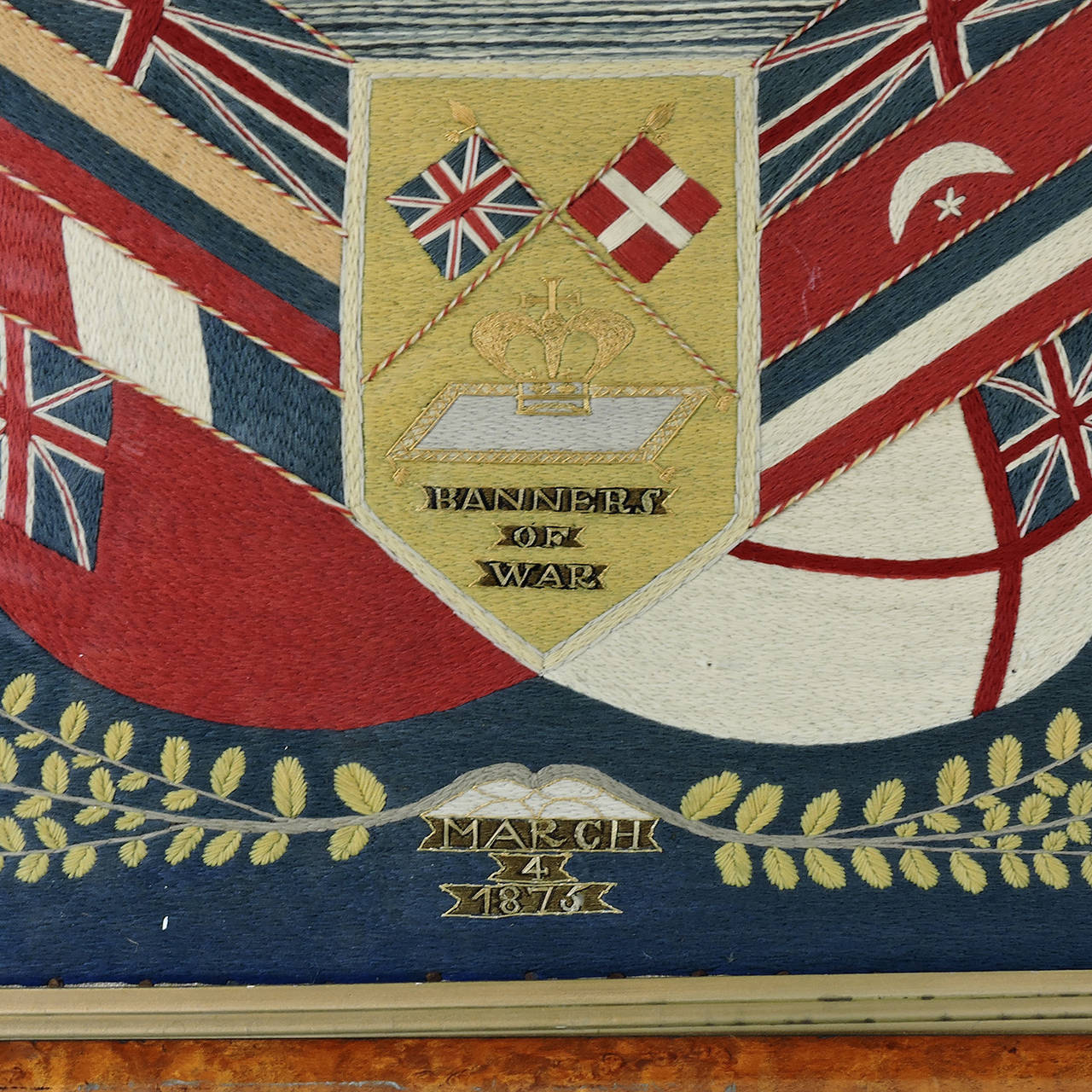 A fine example of a 19th century wool work picture of a British ship decorated with Signal flags from bow to stern, above a royal cartouche that reads 