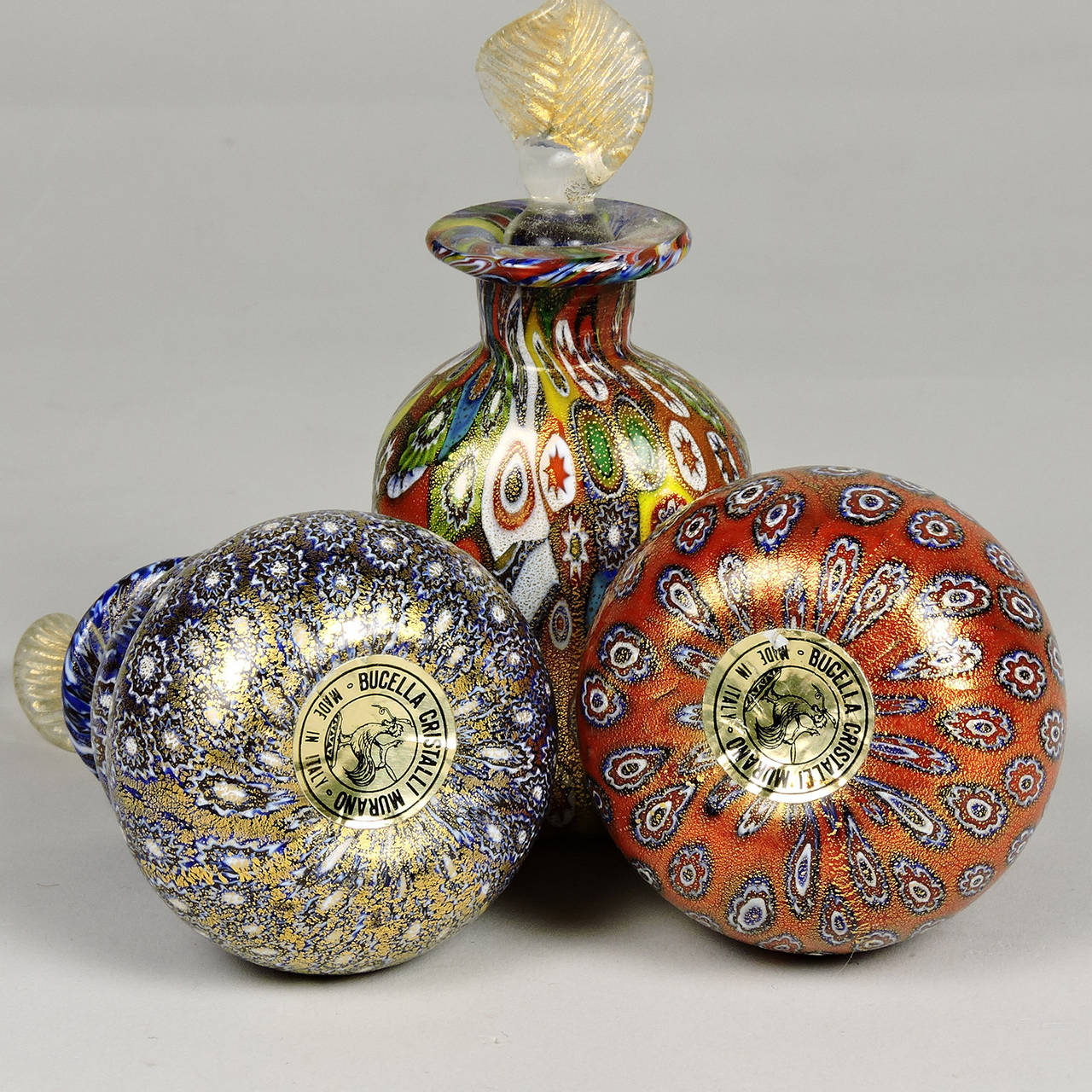 Three vintage Bucella Cristalli millefiori gold aventurine Murano glass perfume bottles. Two with paper labels. Height of tallest: 4 1/2 inches.