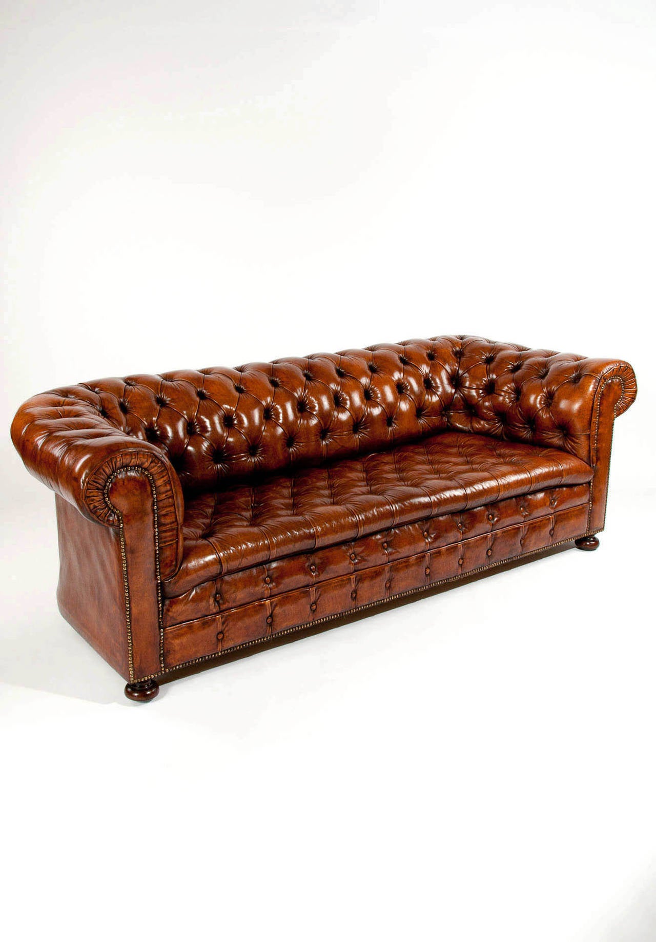 A very good quality deep buttoned leather upholstered Chesterfield sofa. This Chesterfield has a beautifully deep buttoned back with scrolling arms which fall down to a deep buttoned seat. The Chesterfield has a lovely faded brown / tan color and