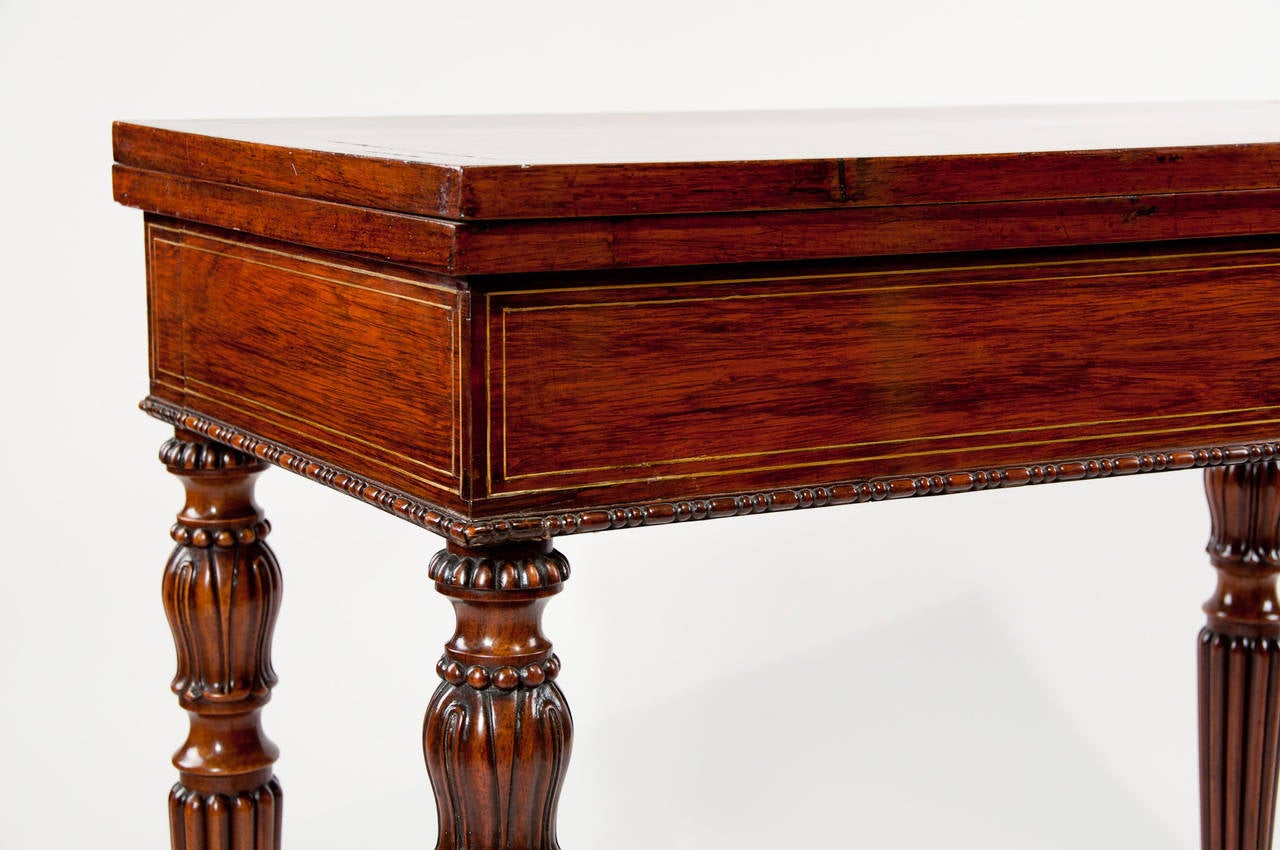 A fine quality Regency / WIV rosewood card table with a brass stringing inlay which borders the top and all sides. The card table opens up to reveal a circular black baize centre inset lovely patinated rosewood. This handsome piece stands on Gillows