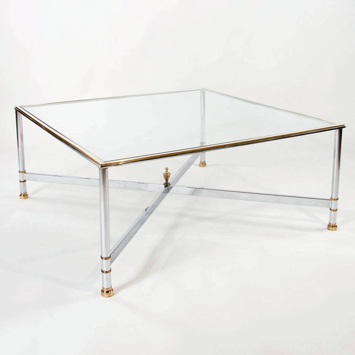 A large 1970s Square coffee table in chrome and brass with a glass top. This sleek coffee table made in the manner of Maison Jansen dates to the 1970s is extremely good quality having a brass top edge with a cross frame stretcher supported by four
