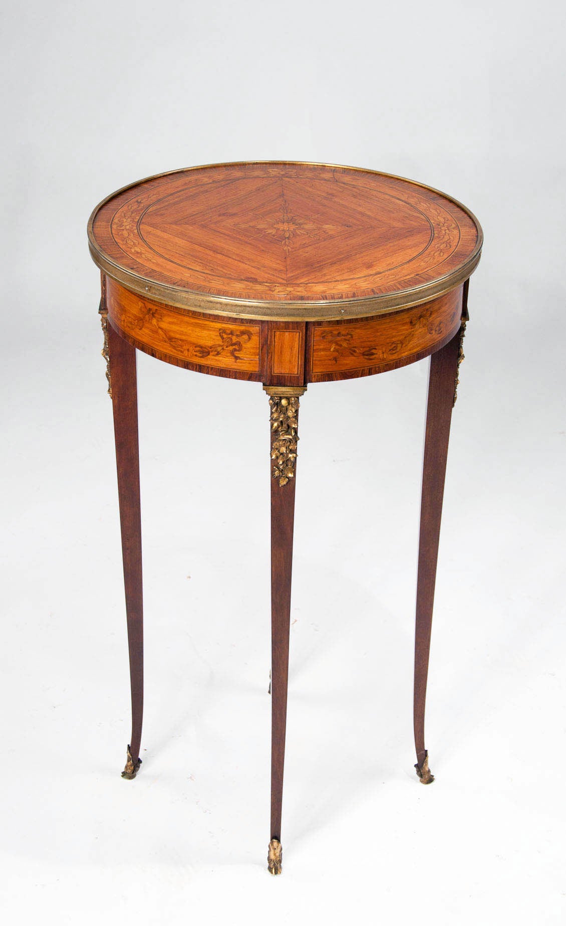 A very fine French inlaid occasional table with gilt mounts and banding. This superb quality occasional table dating to circa 1900's has round kingwood floral inlaid top with rosewood crossbanded board and gilt reeded edge band, the satinwood frieze
