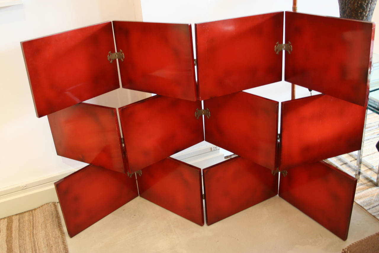 Three levels each with decorative butterfly hinges which fold in opposing directions at different sections.  Piece is lacquered in a russet red with black tonal shading throughout.  De Coene Freres was a Belgian decor and design firm that formed at
