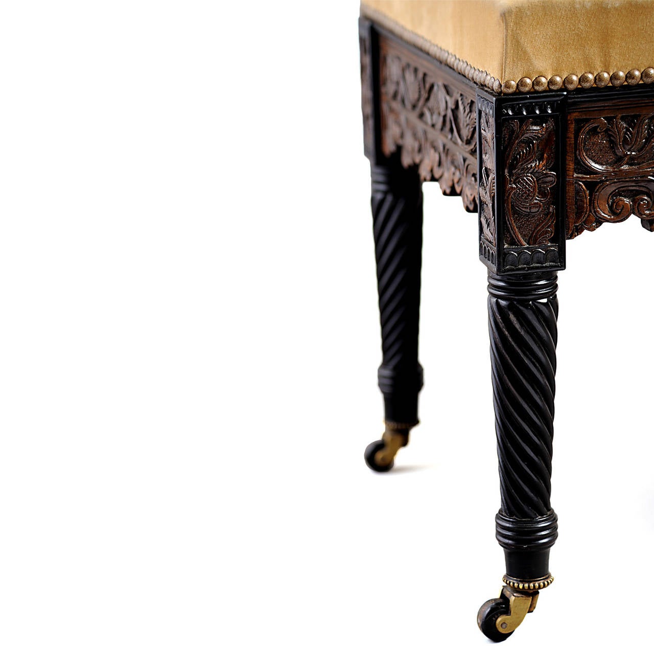 England, circa 1825-1830.

The rectangular close-nailed suede seat above a floral-carved hardwood frieze with framed corner blocks, over ebony wrythen-turned legs, with pipped brass caster-caps stamped COPES PATENT.

Conceived in the manner of