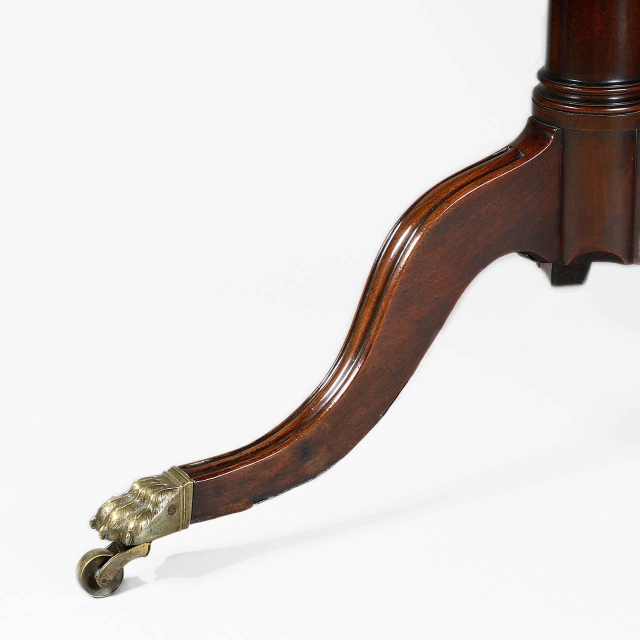 Provenance: Acquired directly from a Lady of title, Monte Carlo.

The circular, figured solid mahogany tilting top having a carved moulded edge, supported on a tapering and turned gun-barrel stem, raised on moulded cabriole legs with brass lions’