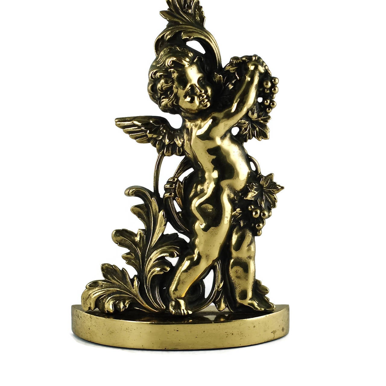This large late Victorian figural doorstop was made by Peerage of England. The piece is composed of cast brass with a cast iron filled base and has been made in the form of a winged cherub standing on a demilune plinth beside scrolling acanthus