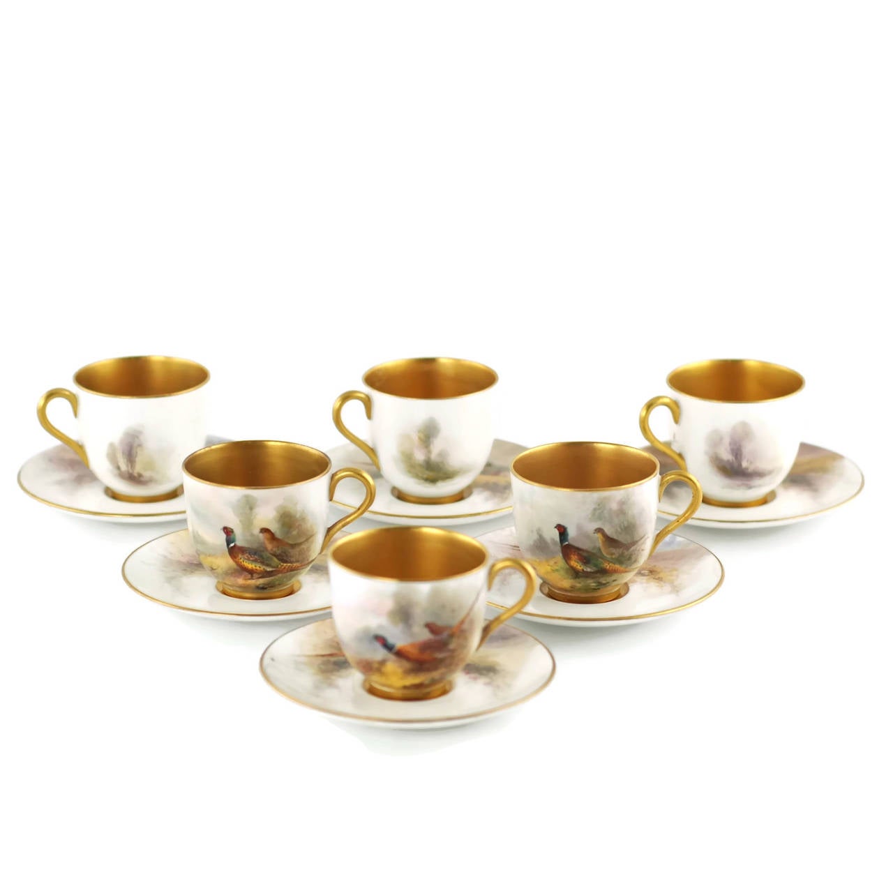 This English porcelain coffee set was manufactured by Royal Worcester and consists of six porcelain cups and six saucers along with six hand-painted enameled sterling silver spoons. The cups and saucers have been decorated with images of ring-necked