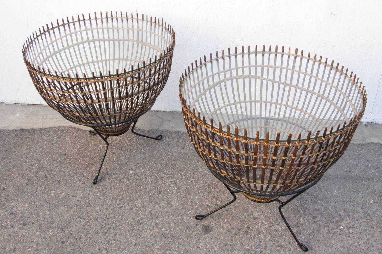 A rare pair of Franco Albini design side tables constructed
of rattan fish baskets set on sculpted iron rod bases topped with inset glass inside bottom and top.
Made in Italy.