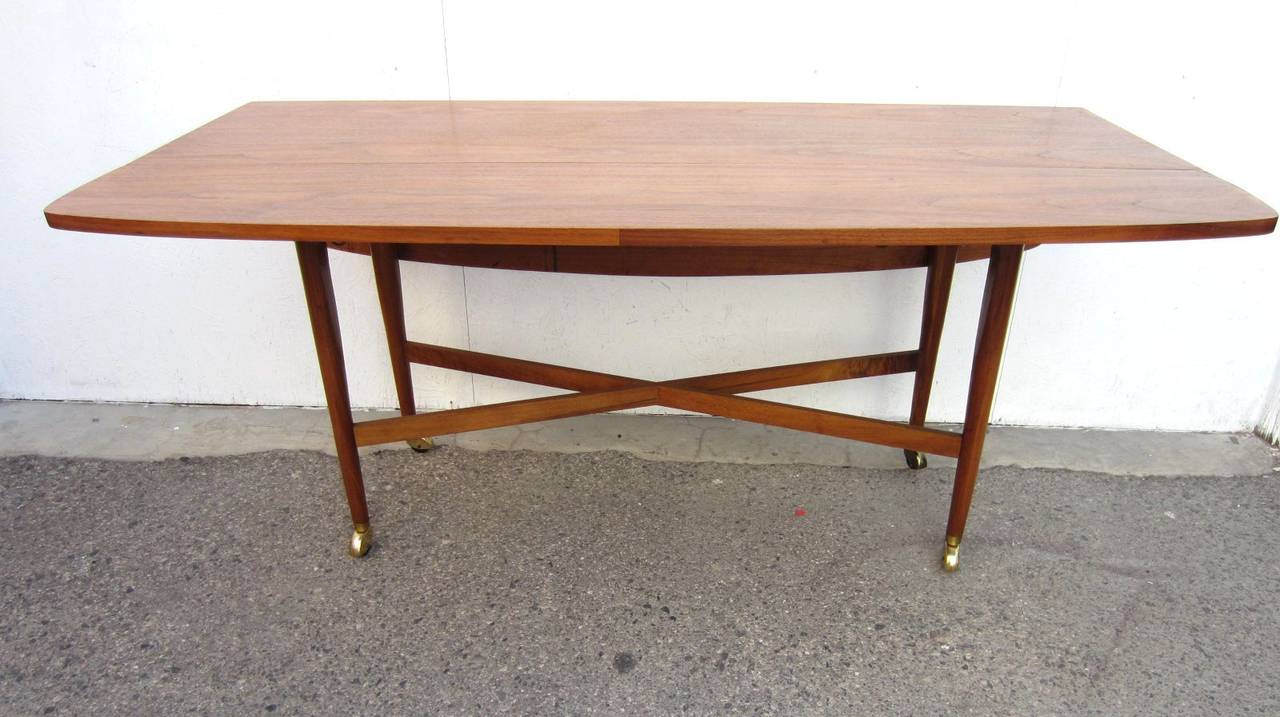 This is Drexel Declaration Model 851-311 drop leaf X base sofa table designed by Kipp Stewart and Stewart Mc Dougall circa 1960(dated on bottom). Made of solid walnut with brass casters and original pad feet attached on the underside if you prefer