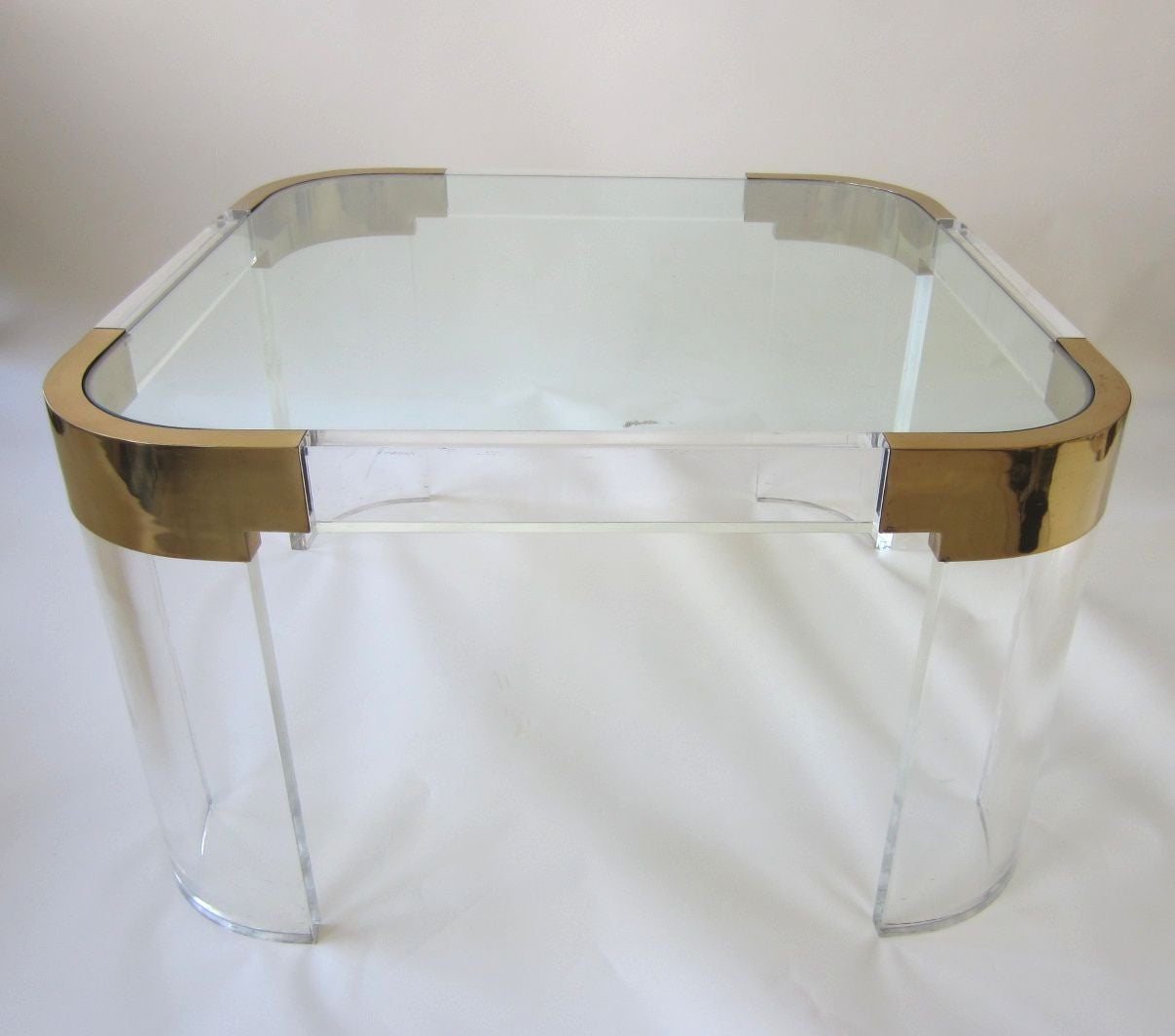 Designed by Charles Hollis Jones this huge vintage table is constructed of thick Lucite legs and side rails with round brass corners and a thick glass top.
A beautiful piece of functional art furniture in exceptional clean condition.